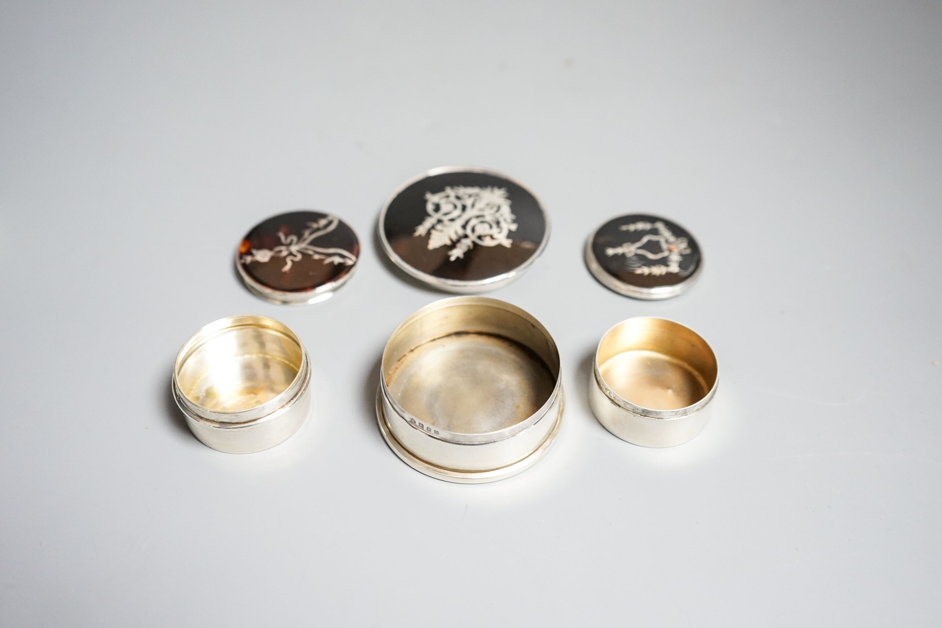 Three assorted early 20th century silver and tortoiseshell pique circular boxes and covers, including William Comyns, largest 63mm.